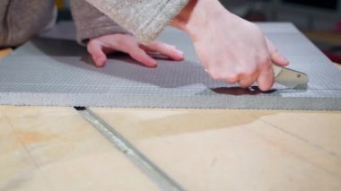 A hand cuts the dense gray foam with a clerical knife. Adjusting the dimensions of the insulation