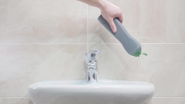 Hand pouring detergent from gray plastic bottle onto white ceramic sink in bathroom — Stock video