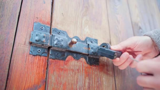 Hands open padlock with key on vintage wooden door with vintage door latch close up — Vídeos de Stock