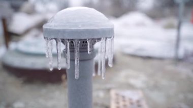 The basement ventilation pipe is iced up and covered with icicles close-up