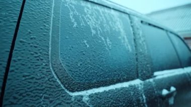 Body of black tinted car iced up after freezing rain in winter