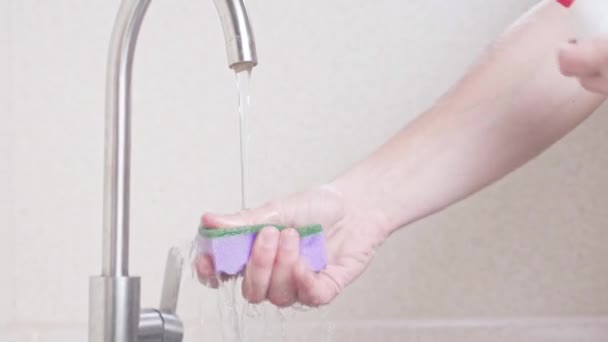 皿の上に洗剤をかける水道水の下のシンクの上にスポンジ — ストック動画