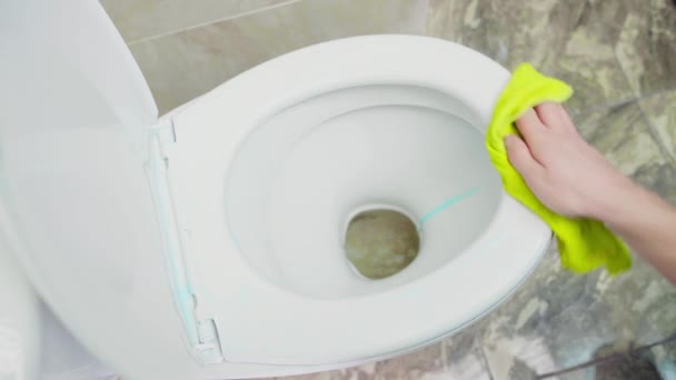 Hand wipes detergent with a yellow rag on the rim of the toilet bowl, top view — Stock Video