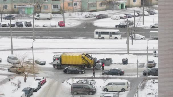 Kiev, Ucrania - 12 de enero de 2022: Los trabajadores cargan la basura de los contenedores de basura en un camión de basura en invierno en las nevadas. — Vídeos de Stock