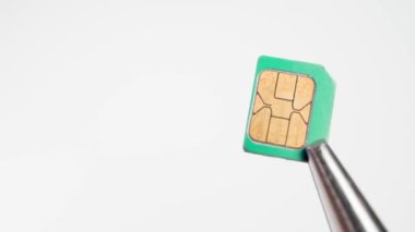 SIM kart mikro-SIM biçimi beyaz arkaplanda pense içinde dönen yakın çekim