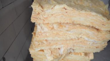 Çatı yalıtımı için paketlenmemiş cam yünler bir inşaat sahasında bulunur.