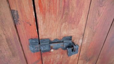 Ahşap kapılarda antika siyah demir kapı mandalı. Ahşap kapı asma kilitli. Yüksek kaliteli FullHD görüntüler