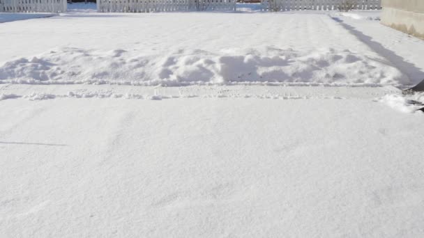 Paleando nieve con una pala en tiempo soleado. Chico paleando nieve — Vídeos de Stock