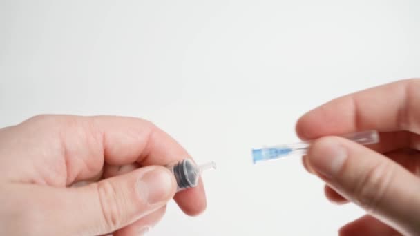 Sätt en nål på en medicinsk spruta och ta bort skyddslocket på en vit bakgrund. — Stockvideo