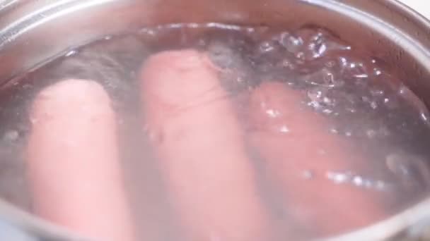 Les saucisses appétissantes sont bouillies dans un gros plan d'eau. Ébullition — Video