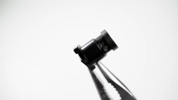 Módulo de câmera escondida close-up em alicates em um fundo branco — Vídeo de Stock