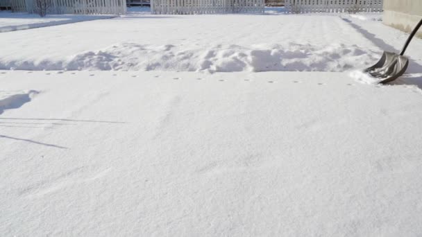 Paleando nieve con una gran pala de plástico gris en tiempo soleado — Vídeos de Stock