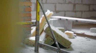 Cam yünler ve mineral yünleri iskelenin arkasında yerde yatıyor. Çatı yalıtımı