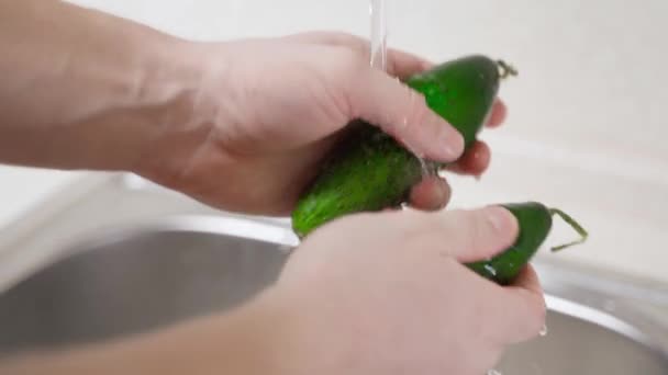 Mãos lavando pepinos verdes frescos sob água corrente na cozinha — Vídeo de Stock