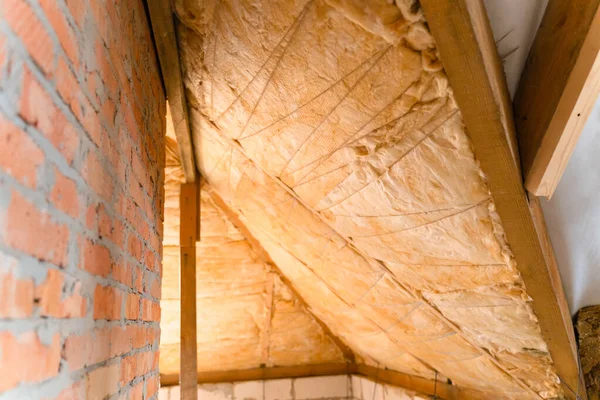 Çatı kirişleri arasında cam yünler seriyorum. Teknoloji ve özel bir evin çatısını yalıtma süreci