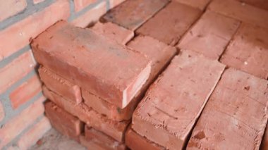 Kırmızı eldivenli bir el, kırmızı seramik bir tuğlayı yakın plan dizer.