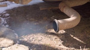 Eski bir dizel arabanın paslı egzoz borusundan gaz verildiğinde duman çıkıyor. Eski arabaların emisyonları ve kirliliği