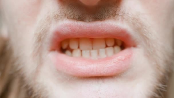 Un joven muestra sus labios de cerca. Tipo con pelo largo, bigote y barba. — Vídeos de Stock