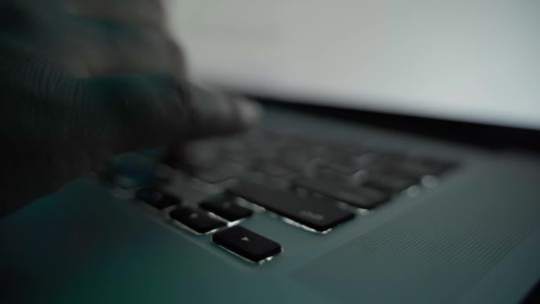 Doigts tapant sur un clavier d'ordinateur portable dans une pièce sombre — Video