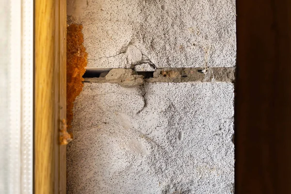 The gap between the window and the wall is filled with mounting foam, close-up. Aerated concrete block wall