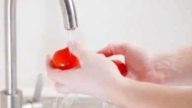 Suyun altında kırmızı domatesleri yıkıyorum. Yakın plan.
