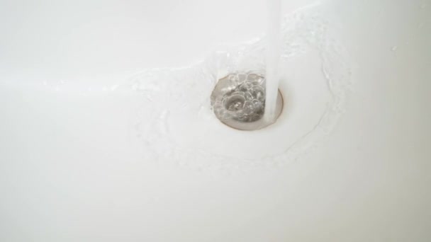 Water flows into the drain hole of a white bathroom close-up — 비디오