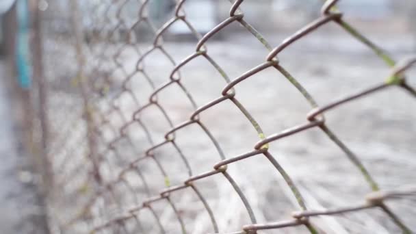 The camera moves along the old rusty mesh fence close-up. Blurred background. — Vídeos de Stock