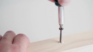 Screwing a black self-tapping screw into a wooden beam close-up. High quality 4k footage