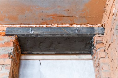 Duvar inşa edilirken bir kapı için ipotek. İki demir köşeden tuğla bir duvarda bir kapı.