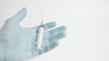 An unrealistic blue hand squeezes a medical syringe on a white background and disappears. Close-up