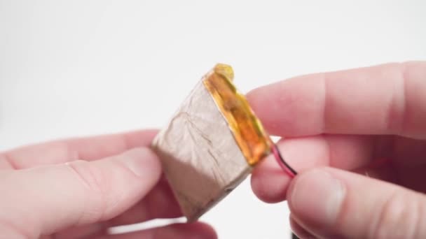 Thin old lithium-polymer battery in a paper shell with an electronic circuit board close-up in hands on a white background — Stockvideo