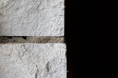 Siyah zemin üzerinde havalandırmalı beton tuğlalardan oluşan bölüm duvarı