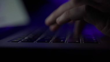 Dizüstü bilgisayarında renkli ışıklarla karanlıkta yazı yazan eller. Sallanan kamera ve bulanık arkaplan