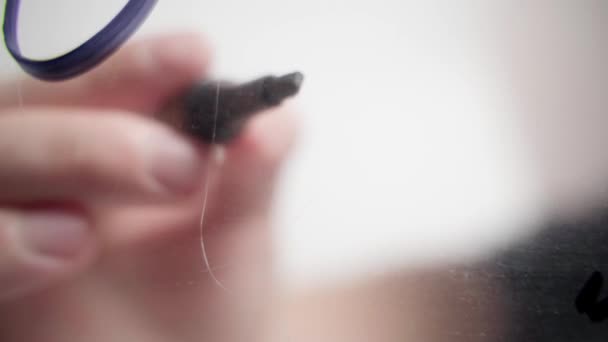 Hand ritar ett hjärta på ett genomskinligt glas med en svart markör — Stockvideo
