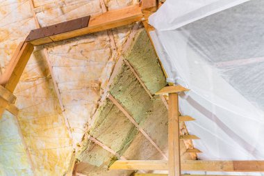 Çatıdaki iki katman izolasyon buhar bariyeriyle kaplıdır. Tavan kirişleri arasında kademeli olarak sarı cam yünü ve yeşil mineral yünü döşeme.