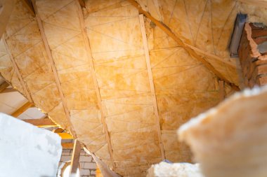 Çatı kirişleri arasında cam yünler seriyorum. Teknoloji ve özel bir evin çatısını yalıtma süreci