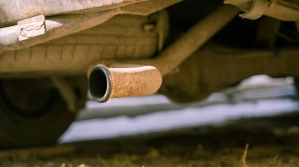 Exhaust pipe of a car in sunny weather. Rusty bottom. Air emissions