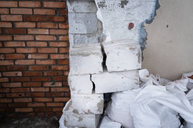Özel bir evin arka planında inşaat enkazı var. Sökülmüş duvar yalıtımı. Çatlak beton blok
