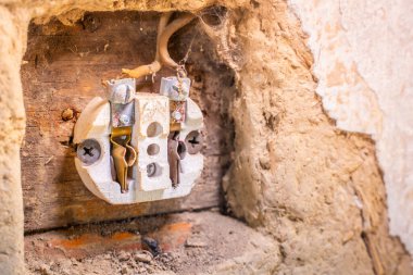 Duvara monte edilmiş eski bir elektrik prizini kil bir duvara yakın çekimde parçaladım. Eski nesil bir elektrik prizinin içi. Kırsal bir evde elektrikçi.