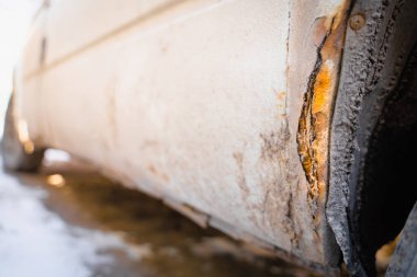 Beyaz bir arabanın paslı çamurluğu. Reaktörlerin kışın korunmasız bir araba üzerinde etkisi. çürük metal