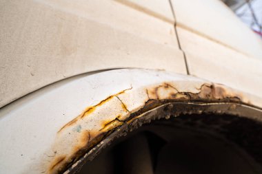 Beyaz bir arabanın paslı çamurluğu. Reaktörlerin kışın korunmasız bir araba üzerinde etkisi. çürük metal