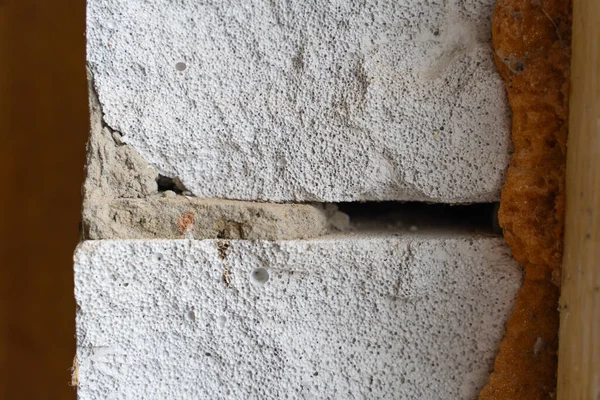 The gap between the window and the wall is filled with mounting foam, close-up. Aerated concrete block wall