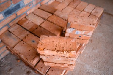 Bir inşaat alanında kırmızı seramik tuğlalar üst üste dizilmiş. yapı malzemeleri