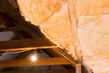 Çatı kirişleri arasında cam yünler seriyorum. Teknoloji ve özel bir evin çatısını yalıtma süreci