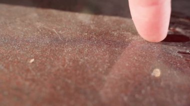 Finger swipes over a dusty dark brown surface close-up. High quality FullHD footage