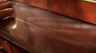 Hand rubbing dust on an old wooden lacquered sideboard close-up. High quality FullHD footage