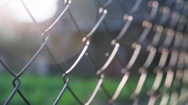 Mesh metal fence close-up with a sun glare. Blurred background, shallow depth of field. High quality FullHD footage