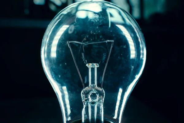 An old light bulb close-up in light highlights on a dark background with blue tones