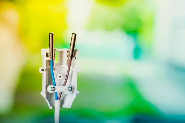 Connecting the wires of an electrical appliance into an electrical plug. Disassembled white plastic electrical plug close-up on a colored blurred background. Brown and blue wire.