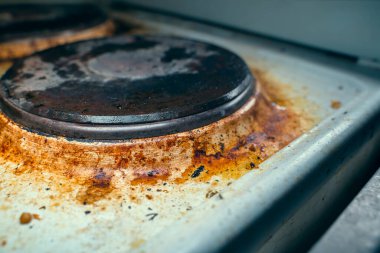 Old kitchen electric stove in heavy brown pollution and soot close up